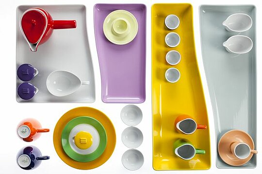 Künstlerische Anordnung von verschiedenfarbigen Tellern und Tassen aus Porzellan