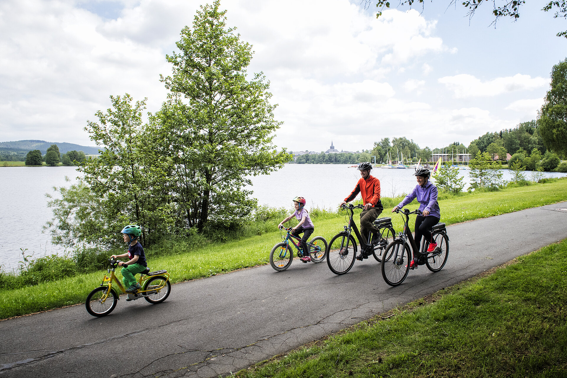 Zwei Erwachsene und zwei Kinder machen eine Radtour am See